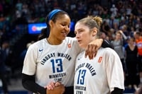 Two basketball players viewed from the waist up, standing next to each other with their right hands clasped.